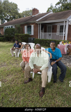 Portrait of interracial couple and family sitting in backyard Stock Photo