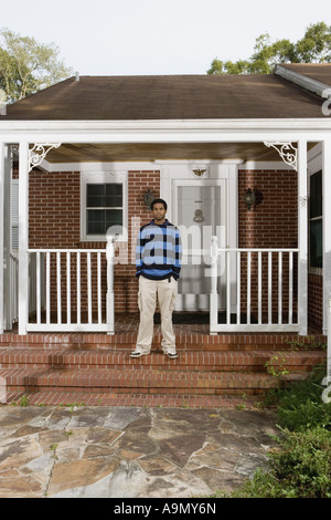 Portrait of a young man standing on front porch of house Stock Photo