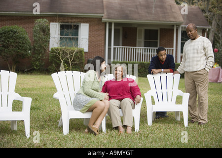 Family and friend relaxing in backyard conversing Stock Photo