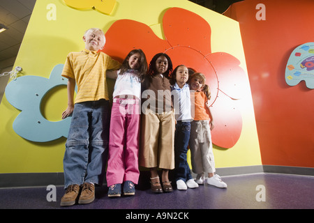 Girls and boy standing against a colorful wall Stock Photo
