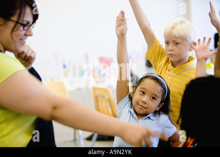 Teacher with her young students raising hands Stock Photo
