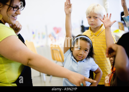 Teacher with her young students raising hands Stock Photo