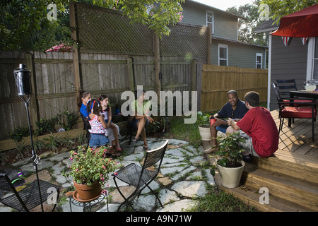 Two families on backyard patio relaxing with cold drinks Stock Photo