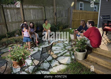Two families on backyard patio relaxing with cold drinks Stock Photo