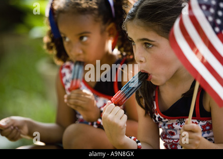 Girls eating popsicles waving US flags Stock Photo