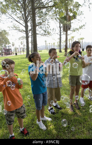 Children blowing bubbles at a park Stock Photo
