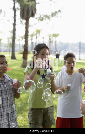 Children blowing bubbles at a park Stock Photo