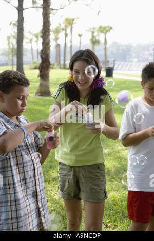 Children blowing bubbles at a park Stock Photo