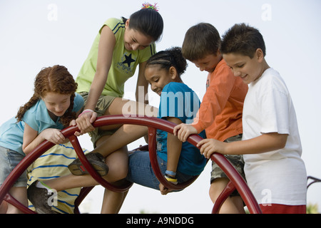 Boys and girls climbing on monkey bars at a playground Stock Photo