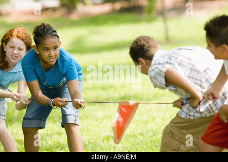 Two boys challenging two girls at tug-of-war at a park Stock Photo