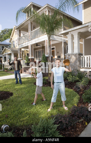 Father and children playing catch in front yard Stock Photo