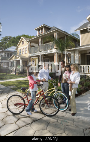 Family with young child conversing with neighbors in front of house Stock Photo