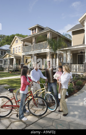 Family with young child conversing with neighbors in front of house Stock Photo