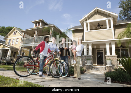 Family with young child conversing with neighbors in front of house Stock Photo