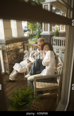 Mature interracial couple sitting on front porch Stock Photo