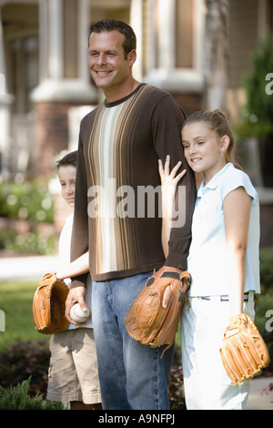 Father and his children standing in front of house with baseball and gloves Stock Photo