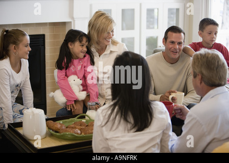 Family and friends having breakfast together in living room Stock Photo