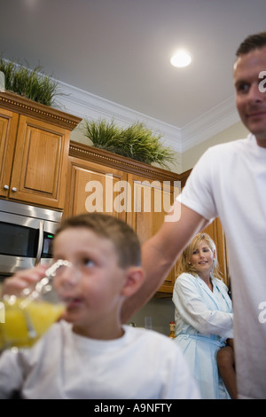 Boy drinking juice with father and mother in background Stock Photo