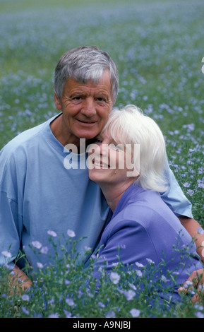 portrait happy mature couple sitting in linseed field Stock Photo