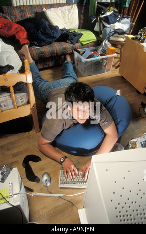 teenage boy computer nerd playing on his computer in his messy room Stock Photo