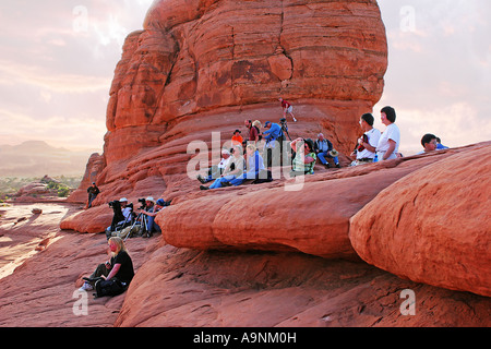 Image of a group of people all with cameras ready sitting among the rock formations in Arches National Park waiting to take a pi Stock Photo