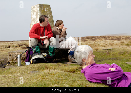 Guided walking group stop for lunch at trig point on Offas Dyke footpath Hatterrall Ridge Wales England border UK Stock Photo