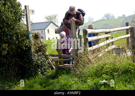 Guided walking group crossing stile on footpath to Longtown in the Black Mountains Herefordshire England UK Stock Photo
