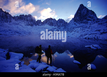 A couple enjoying the view while hiking after a snowstorm in Dusy Basin CA Stock Photo