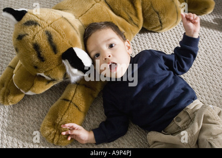 Portrait of a boy lying on a floor with stuffed animal Stock Photo