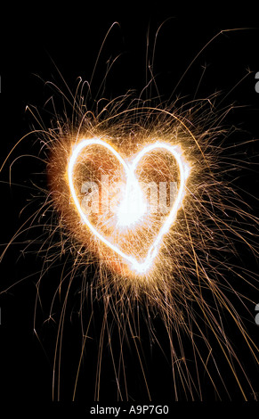 Sparkling heart shape made at night with sparklers Stock Photo