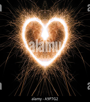 Sparkling heart shape made at night with sparklers Stock Photo