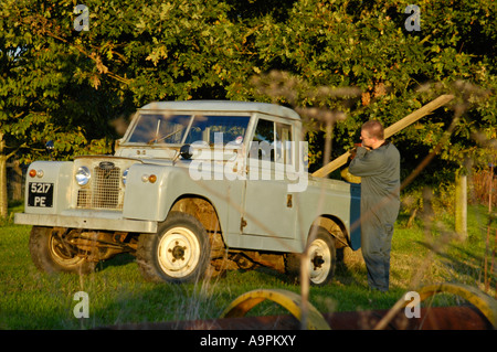Farmer in overall loading timber into an old 1960 s Landrover Series 2a short wheel base truckcab. Stock Photo