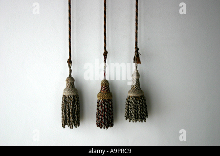 Three decorative tassels hanging against a wall Stock Photo