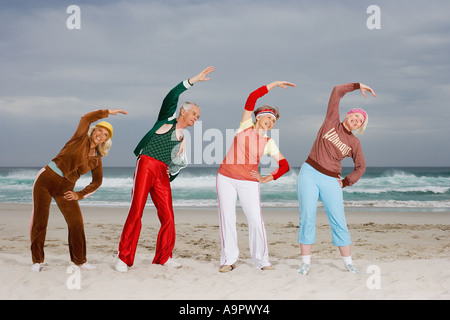 Four senior adults stretching on beach Stock Photo