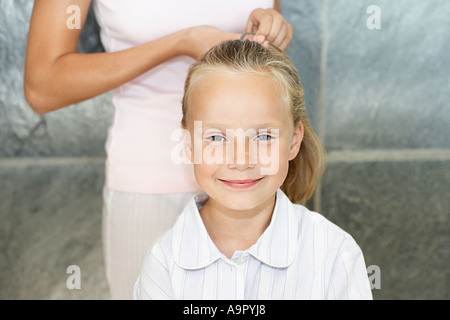 Mother tying her daughters hair back Stock Photo