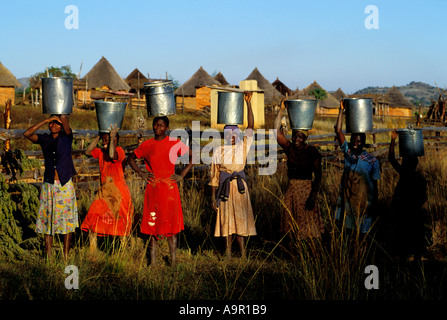 Young women porting buckets of water into rural Zimbabwe village Stock Photo