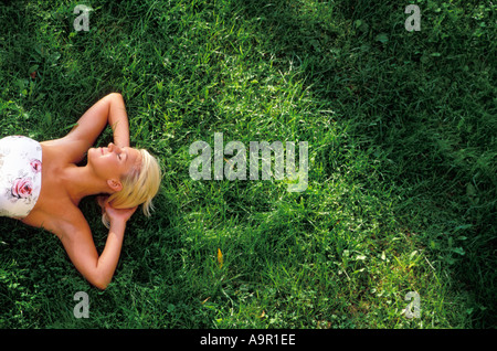 Young lady in summer dress resting on grass Stock Photo
