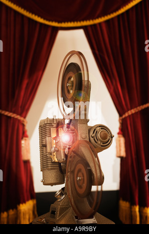 Old fashioned movie projector in between stage curtains Stock Photo