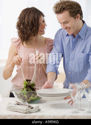 Couple setting table and tossing salad Stock Photo