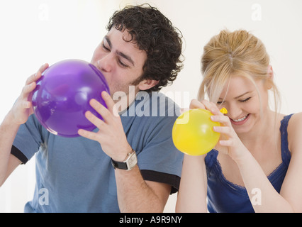 Couple blowing up balloons Stock Photo