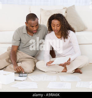 Couple paying bills on floor Stock Photo
