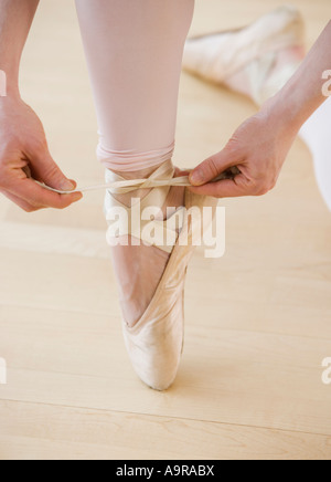 Female ballet dancer tying pointe shoes Stock Photo