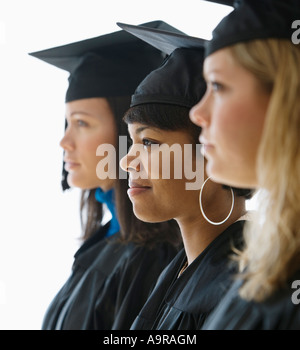 Multi ethnic women wearing graduation cap and gown Stock Photo