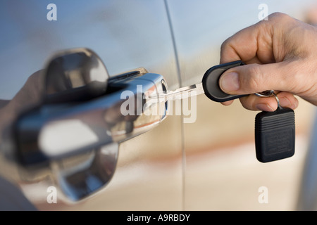 Man putting car key in door Stock Photo