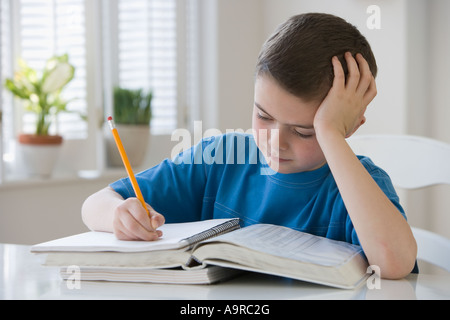 Boy doing homework at table Stock Photo