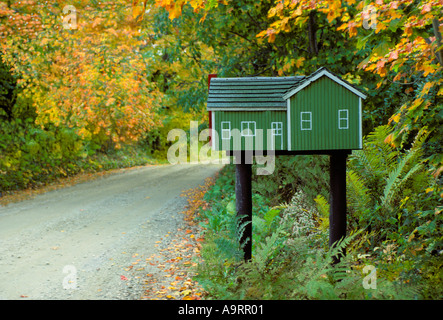 Small model house built as mailbox standing by a lone country road Stock Photo