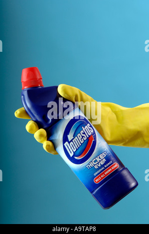 generic of yellow cleaning gloves holding Domestos bleach Stock Photo