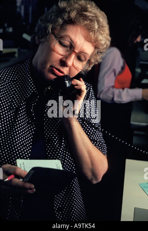 Female caucasian bank teller on phone w customer Stock Photo