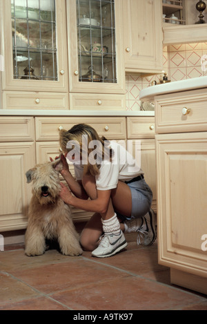 Young caucasian housewife kitchen floor w pet family dog Stock Photo