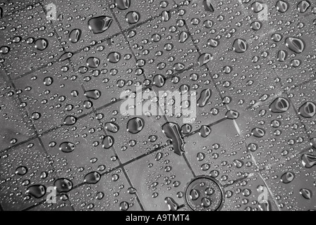 Abstract arrangement of rainwater droplets on grid marks on new plastic garden table color removed Stock Photo